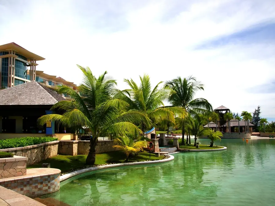 Jardines de un resort con palmeras, césped y terrazas ajardinadas junto al agua