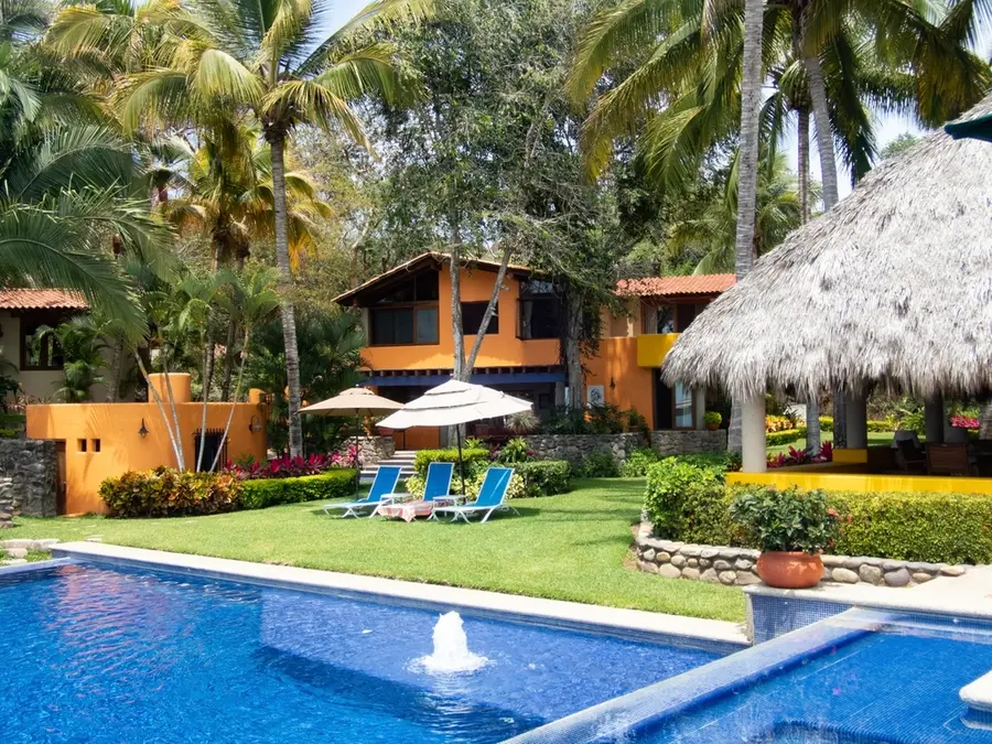 Villa con césped, parterres de flores y piscina bajo las palmeras